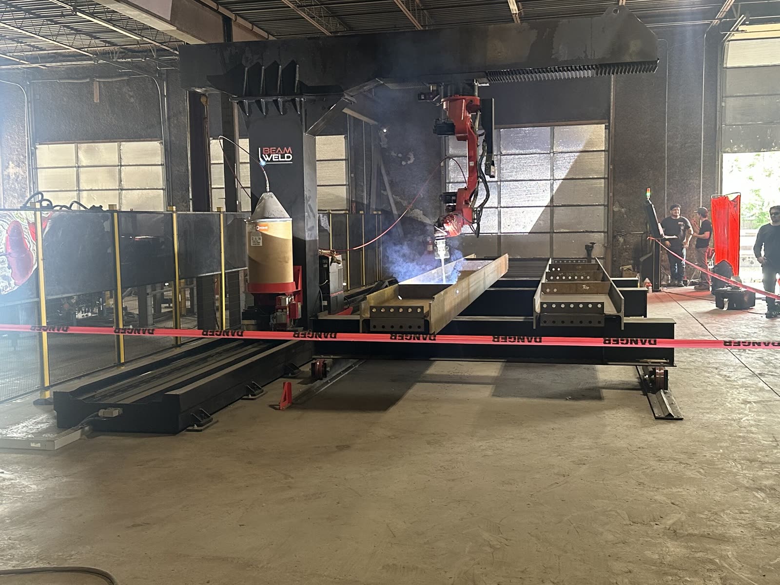 Automated beam welding equipment working on structural steel inside the Flawless Steel Welding shop.