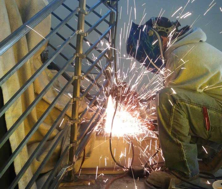 A close-up of a well-trained welder working on stair railings.